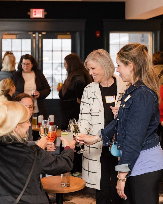 Group of women toasting with drinks in a social setting at Belvedere Lenox, emphasizing connection and celebration for events like weddings and gatherings.