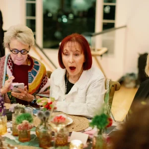 Woman with surprised expression at a festive table surrounded by guests, celebrating a special event at Belvedere Lenox venue.